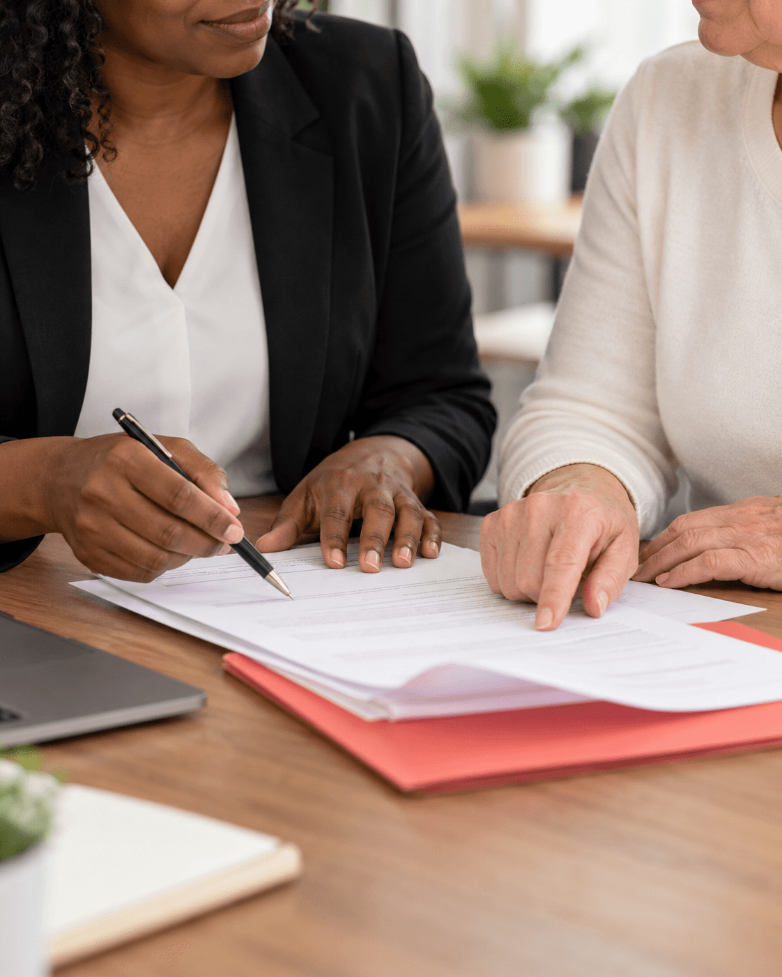 Two professionals reviewing and signing documents at a wooden desk